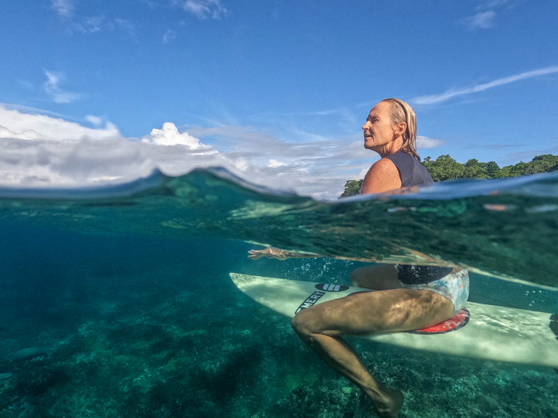 Female surfer sitting on her surf board in the water, Ravenga Surfing Expedition 2022, Ravenga island, Banks islands, Torba Province, Vanuatu. Photo: Vanuatu Tourism Office