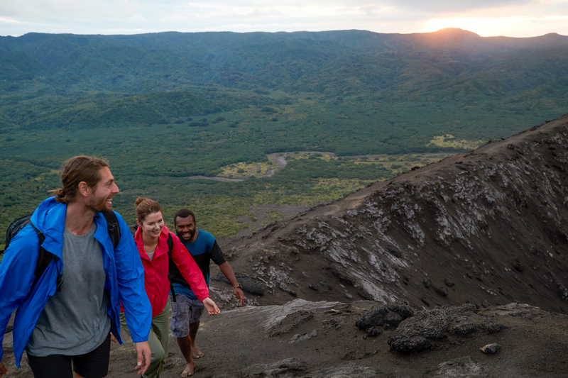 A couple and a local guide walk near the crater of Mount Yasur volcano, Tanna Island, Vanuatu.